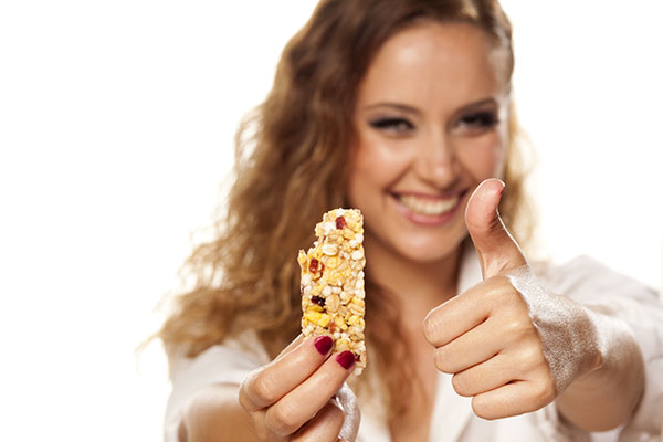 beautiful girl in a white shirt eats fruit bar and showing thumbs up